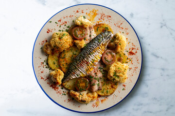 baked mackerel with braised cauliflower and cherry tomatoes. top view table.