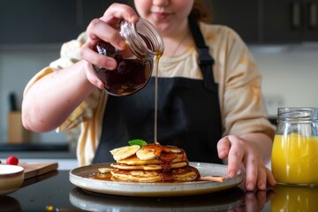 Wall Mural - A girl drizzling mapple syrup over some freshly cooked pancakes