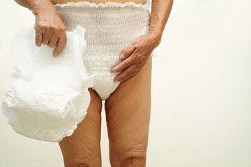 Asian senior woman patient wearing adult incontinence diaper pad in hospital.