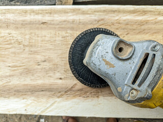 Electric grinding machine with sandpaper blade on wooden board. Wood smoothing and polishing tools. Close up.