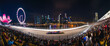 © master1305 - Panoramic image of vibrant nighttime scene of a Formula 1 race in a city setting. Tribune of spectators watching race event.