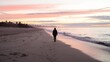 © PixelPerfectionist77 - Lone traveler walking along an empty beach at sunrise