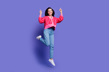 Sticker - Full length photo of charming positive woman wear pink cardigan jumping high pointing up empty space isolated purple color background