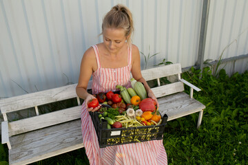 Woman sitting on wooden bench holding basket of fresh vegetables. Concept of eating healthy food to maintain balanced lifestyle