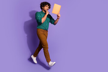 Canvas Print - Photo of thoughtful intelligent mexican man university student in green shirt reading book touching chin isolated on violet color background