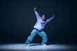 © master1305 - Youthful energy. Dynamic image of young girl, hip hop dancer performing on stage with passion against navy blue studio background. Concept of freestyle dance, modernity, urban culture, youth