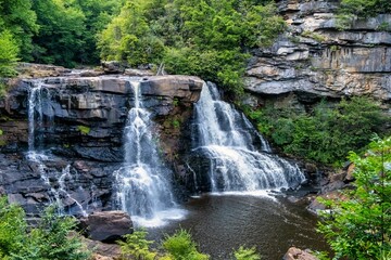 Sticker - Stunning Blackwater Falls State Park cascading over rocky cliffs surrounded by lush green forest