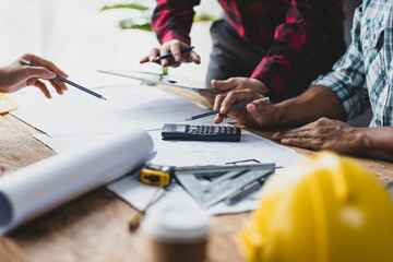 Brainstorming group of architects and engineers discuss building blueprint design paperwork and drawing construction project planning on wooden table in office. Construction project budget planning.