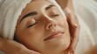 © MarkFinal - close-up of a woman receiving a facial massage, with warm towels and soothing essential oils in a relaxing spa environment