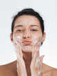 © Buyanskyy Production - Cute Woman Making Face While Washing with Foam, Skincare and Beauty Concept