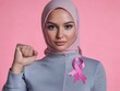 © shooreeq - Bald pretty arab woman showing fist, pink ribbon lapel pin - symbol of the fight against breast cancer on her clothes, bright solid background