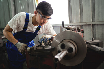 Canvas Print - A man in a blue apron is working on a machine. He is wearing safety glasses and gloves