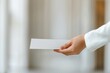 © Vilaysack - Closeup of a hand holding and offering a white envelope, symbolizing communication, invitation, or formal correspondence