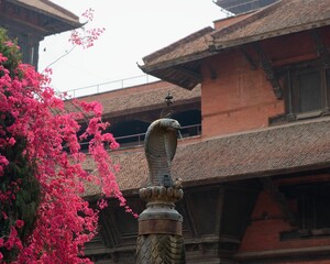 Wall Mural - Traditional Nepali architecture with cobra statue and pink flowers