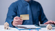 © Mdisk - A professional individual holds a credit card while surrounded by financial documents and miniature house models, highlighting essentials of effective money management and home financing strategies
