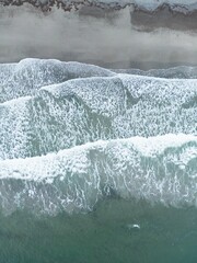 Wall Mural - Aerial view of ocean waves crashing onto the shore