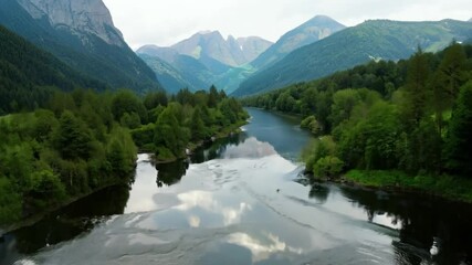 Poster - Drone footage of a tranquil river in a green valley, with mountains in the background in daytime