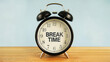 © Lahiru - An alarm clock with the text 'BREAK TIME' in the middle of it on a wooden surface and blue background.