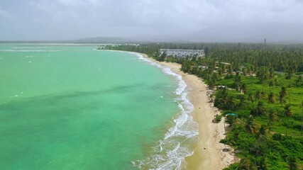 Wall Mural - Drone view of green beach in Loiza, Puerto Rico, with calm sea waves on a cloudy day