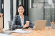 © kenchiro168 - Professional woman smiling with coffee at modern office desk