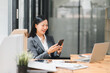 © PRIME STOCK LAB - A professional woman smiles while using her smartphone in modern office