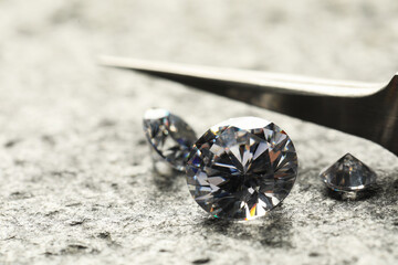 Wall Mural - Many beautiful shiny diamonds and tweezers on grey textured table, closeup. Space for text