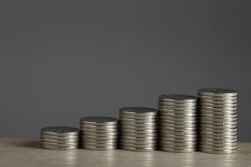 Wall Mural - Stacked coins on wooden table against grey background, closeup with space for text. Salary concept