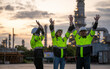 © APchanel - Engineer industry jackets and hard hats standing in an industrial area,  refinery or power plant. They are raising their hands in a safety drill or as a gesture of acknowledgment is teamwork concept.