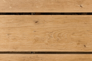 Close up of light brown wood grain with knots, forming a panel, with a thin black line between two planks.