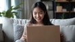 © Phatharaporn - Happy Woman Opening a Package on the Sofa.