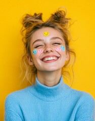 Joyful young woman with playful stickers smiling against bright yellow background