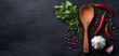 © Kittipong - Black Slate with Chili Peppers Parsley Garlic and Wooden Spoon A Culinary Still Life Composition