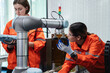 © NewSaetiew - Student engineer assembles a robotic arm in a technology workshop. Engineer holds a robot controller and inspects the robotic arm's welding hardware.