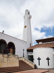 Wall Mural - White church with a tall clock tower and crosses on the walls under a partly cloudy sky in Guatavita