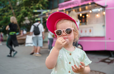 Portrait of a beautiful Caucasian child girl toddler in sunglasses in summer in the city.