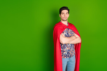 Sticker - Photo of serious confident guy dressed print shirt red cloak hold arms folded near logo empty space isolated on green color background