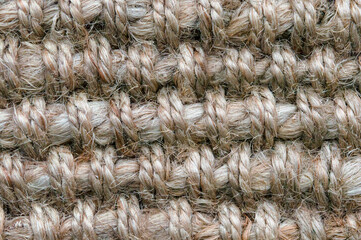 A macro image of a light brown jute carpet.