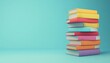 © raja - A Stack of Colorful Books on a Teal Background
