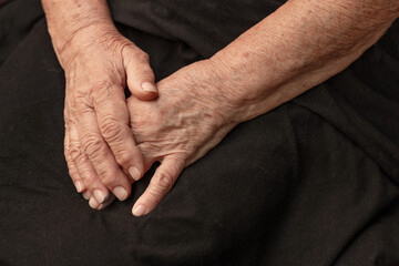 Aged hands of an elderly woman on a black background