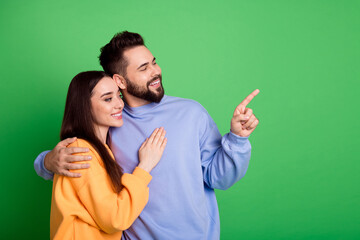 Poster - Photo of charming lovely couple wear trendy clothes look empty space isolated on green color background