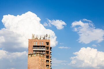 Wall Mural - white clouds in blue sky and high-rise brick house