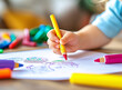 © mertingen - A child coloring with crayons at a table full of colorful stationery