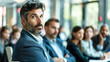 © sommersby - A man looks thoughtfully at the speaker while others remain focused on the presentations during a professional conference