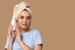 © Pixel-Shot - Young woman with bottle of cream on brown background, closeup