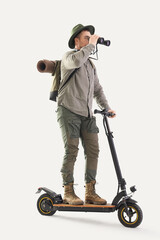 Canvas Print - Young male tourist looking through binoculars while riding kick scooter on white background