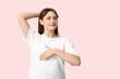© Pixel-Shot - Young woman checking her breast on light pink background