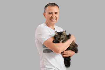 Poster - Mature man holding cute cat on grey background