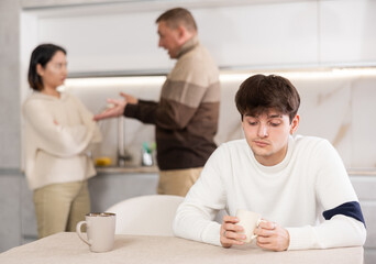 Canvas Print - Angry young guy is tired of domestic quarrels. Relatives quarreling in the background