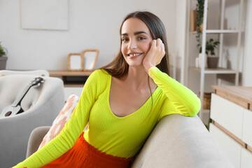 Poster - Young pretty woman sitting on sofa at home