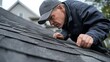 © raja - A roofer inspecting a shingle roof for damage